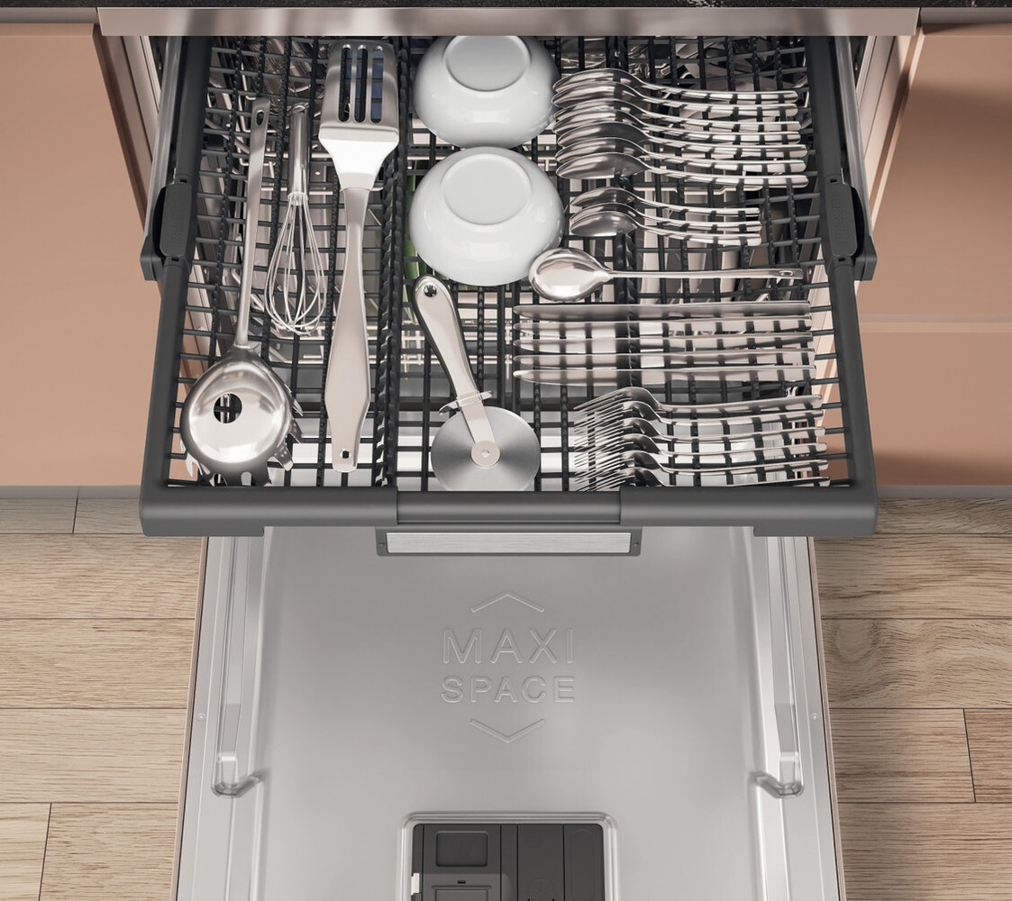 A top-opened dishwasher showing an organized cutlery rack with forks, spoons, knives, and small plates. The interior features a labeled 'MAXI SPACE' compartment on the dishwasher door.