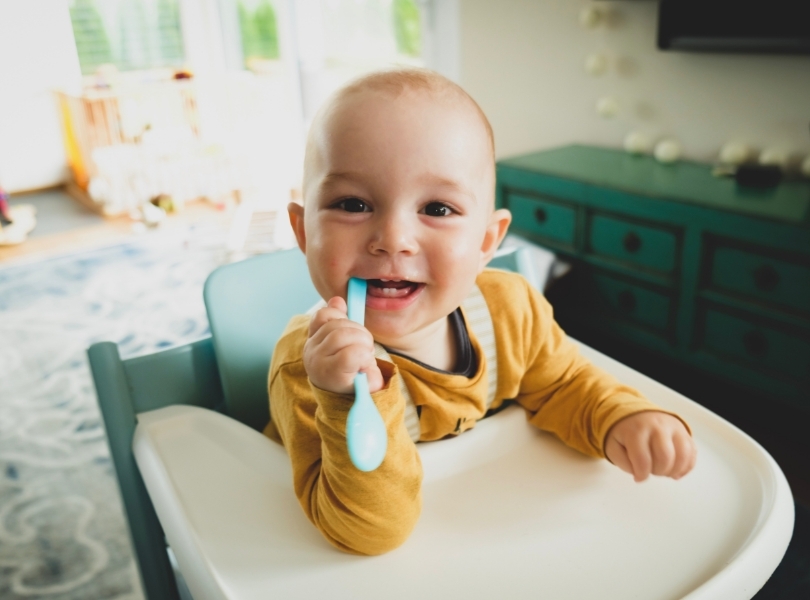 Baby with a spoon in a chair