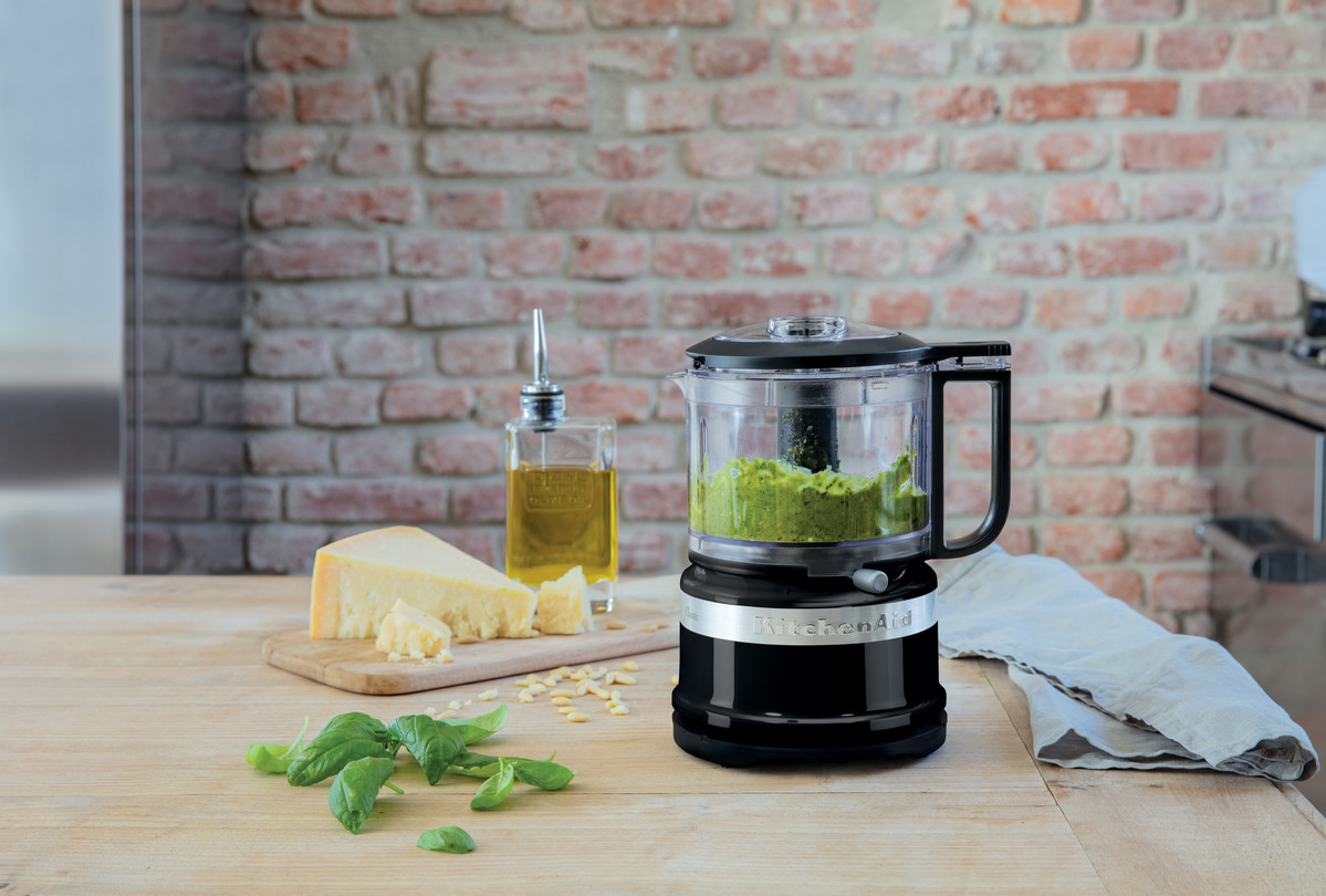 Black mini food chopper preparing green pesto