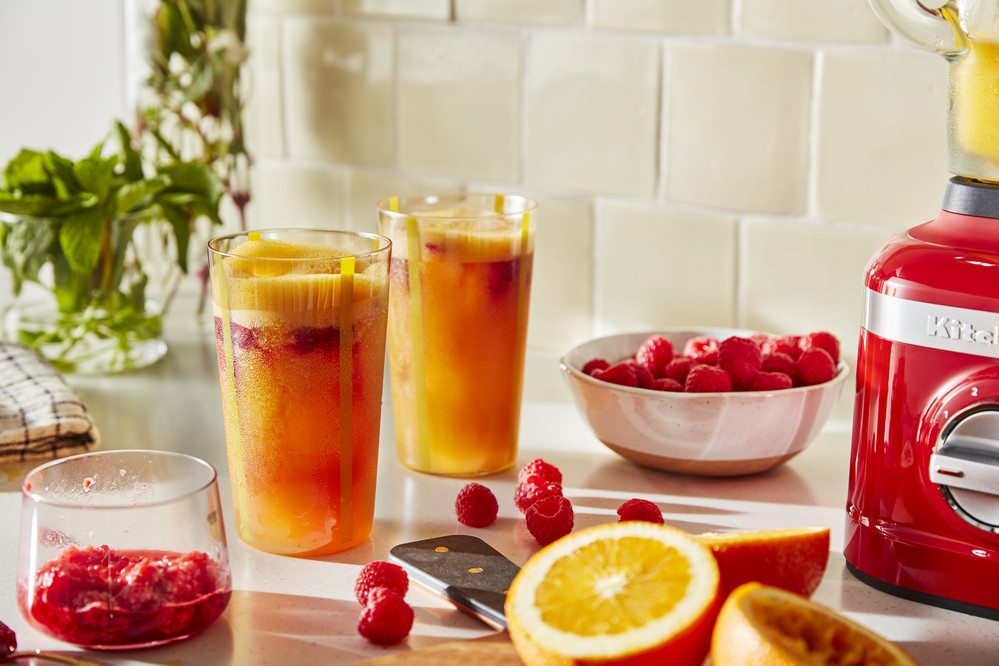 Two glasses of fresh orange and raspberries fruit juice