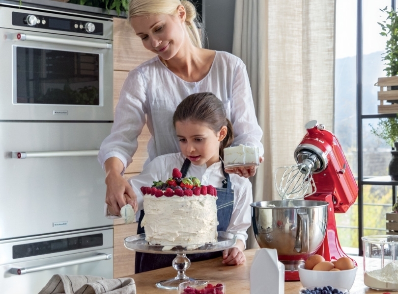 Mom and daughter making cake with red fruits with red mixer
