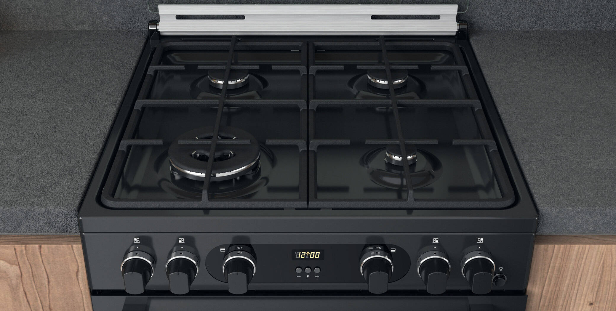 A close-up of a black gas stovetop showing two burners with metal grates. Below, three control knobs and a digital clock are visible on the front panel.