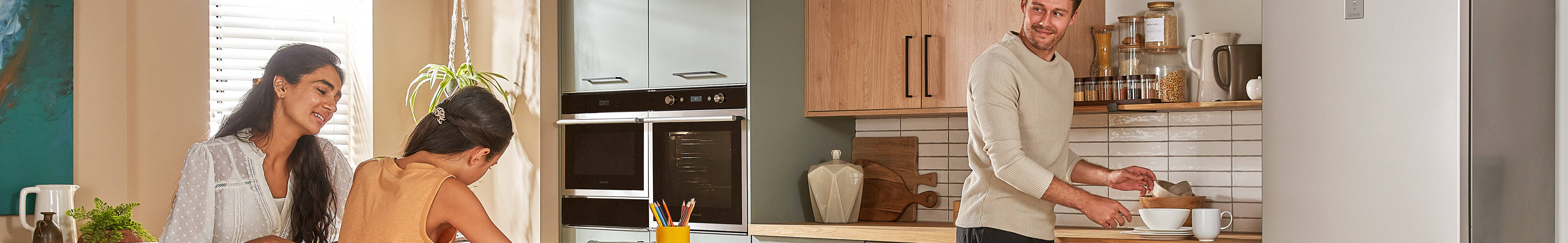 Family in a modern kitchen: a woman and child at a counter, and a man unloading the dishwasher.